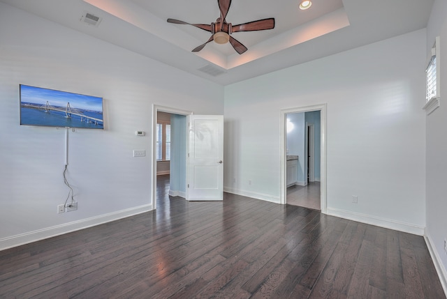 unfurnished room with ceiling fan, a tray ceiling, and dark hardwood / wood-style floors