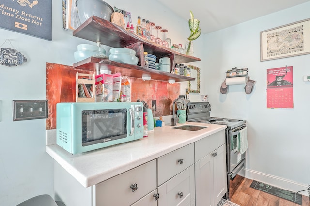 kitchen with sink, white cabinetry, stainless steel appliances, and wood-type flooring