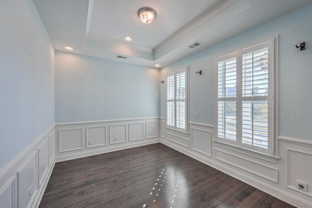 spare room with a tray ceiling and dark hardwood / wood-style floors