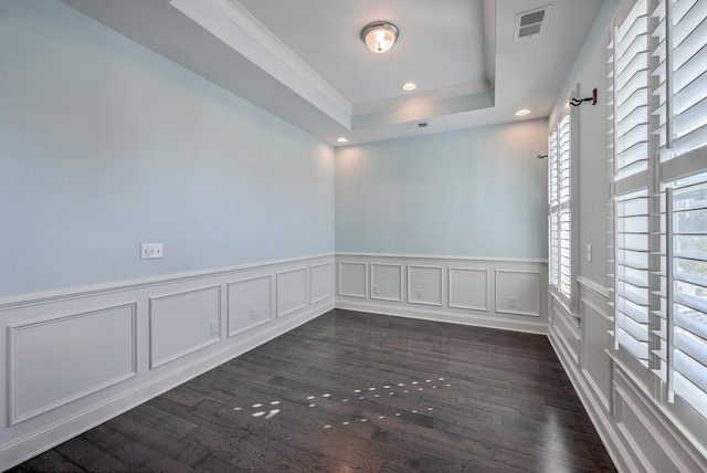 spare room with dark wood-type flooring, a raised ceiling, ornamental molding, and plenty of natural light