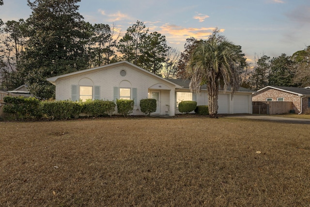 ranch-style home featuring a garage and a yard