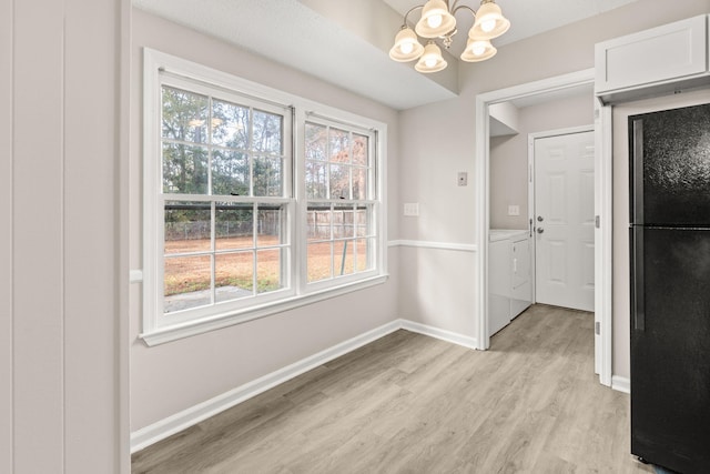 unfurnished dining area with plenty of natural light, washer and dryer, light wood-type flooring, and an inviting chandelier