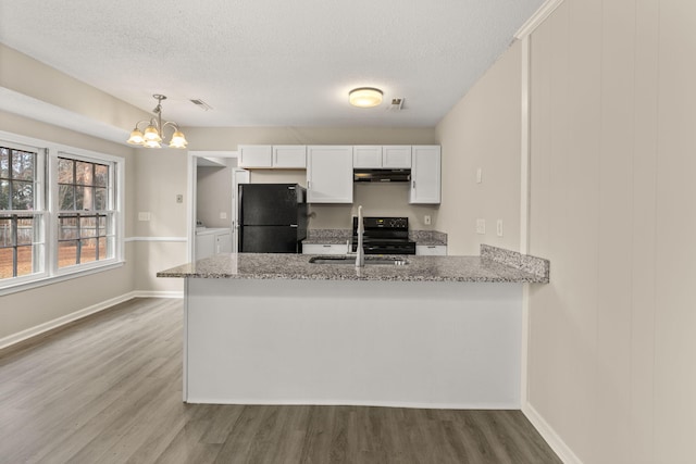 kitchen featuring kitchen peninsula, black appliances, pendant lighting, washing machine and dryer, and white cabinetry