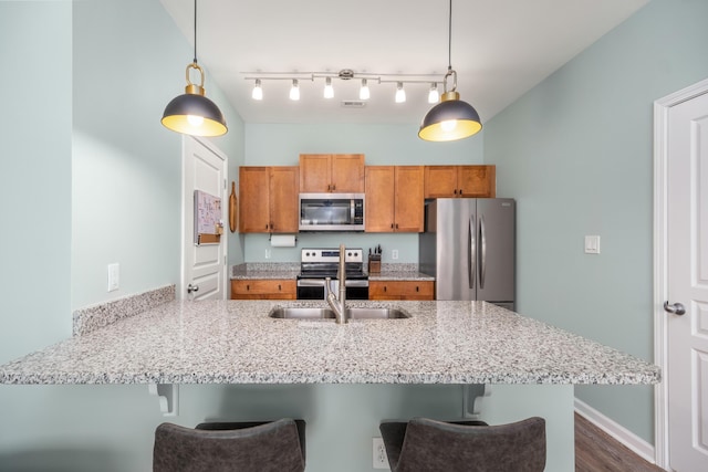 kitchen featuring decorative light fixtures, kitchen peninsula, stainless steel appliances, and a breakfast bar