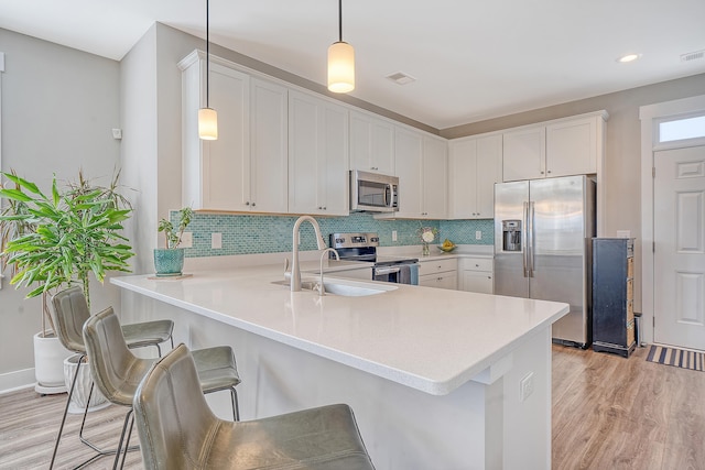 kitchen with visible vents, decorative backsplash, light wood-style flooring, stainless steel appliances, and a sink