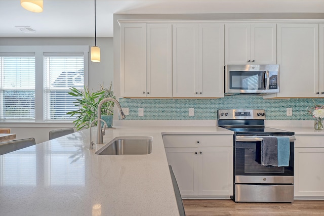 kitchen featuring stainless steel appliances, tasteful backsplash, a sink, and light wood-style flooring