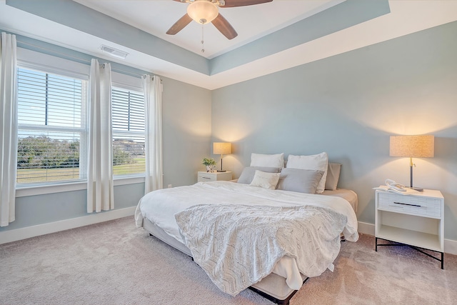 bedroom with baseboards, carpet, visible vents, and a tray ceiling