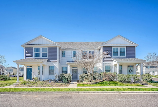 multi unit property with a shingled roof, board and batten siding, and a front yard