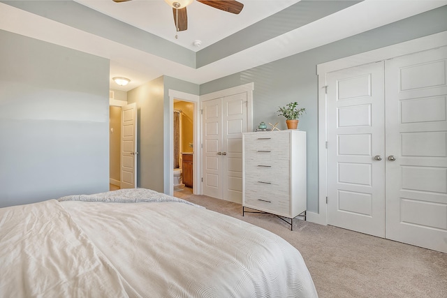 bedroom featuring a ceiling fan, light colored carpet, and connected bathroom