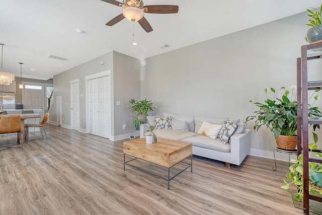 living room featuring light wood-style floors, visible vents, ceiling fan, and baseboards