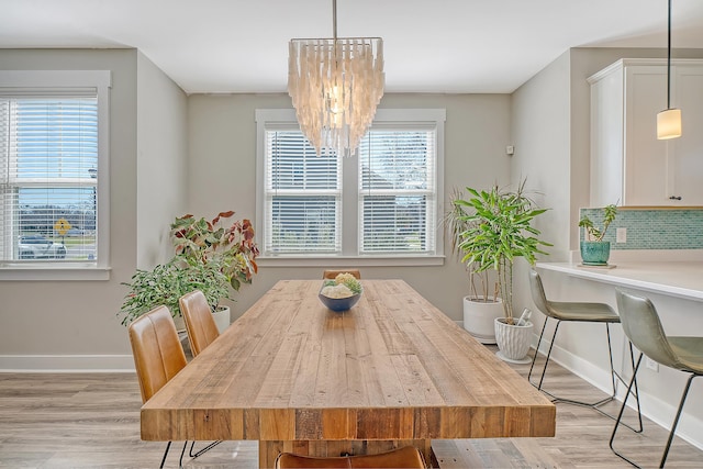 dining area with light wood-style floors, baseboards, and a chandelier