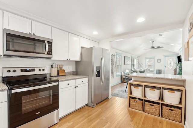 kitchen featuring appliances with stainless steel finishes, white cabinetry, light wood finished floors, and light stone counters