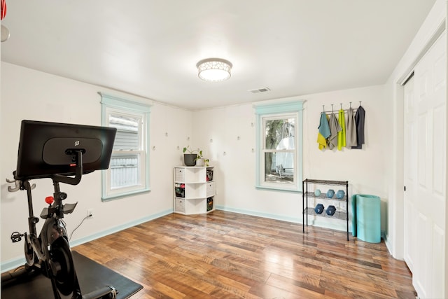 workout area featuring visible vents, baseboards, and wood finished floors