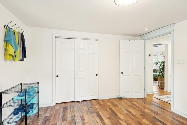 unfurnished bedroom with a closet, baseboards, and wood finished floors