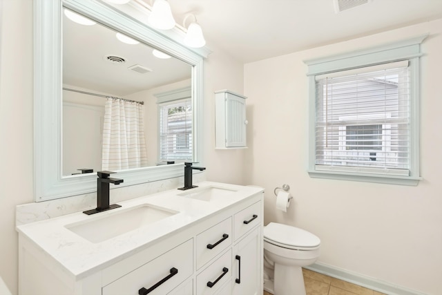 bathroom with double vanity, a sink, toilet, and tile patterned floors