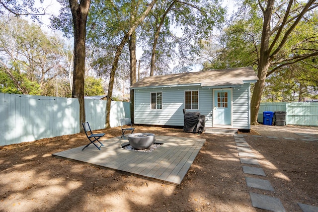 rear view of house featuring an outdoor fire pit, a fenced backyard, and an outdoor structure