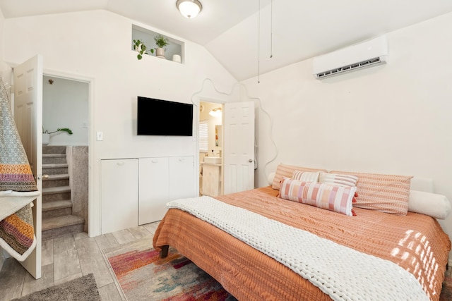 bedroom featuring wood finish floors, vaulted ceiling, and a wall mounted AC