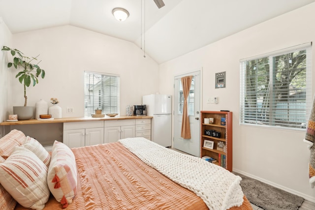 bedroom with baseboards, vaulted ceiling, and freestanding refrigerator