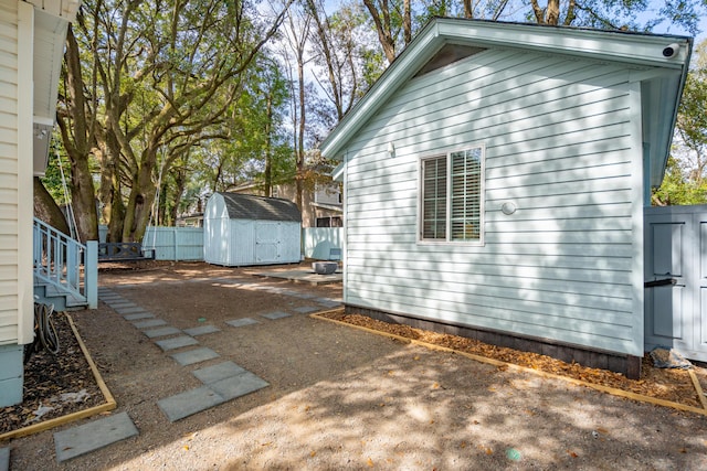 view of home's exterior featuring a storage shed, an outdoor structure, and fence