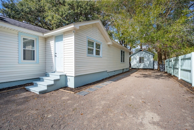 view of side of property featuring driveway, fence, and an outbuilding