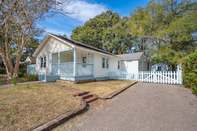 view of front of home with covered porch, crawl space, fence, driveway, and a front lawn