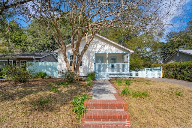 bungalow featuring fence, a porch, and a front yard