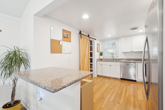 kitchen featuring white cabinets, a barn door, a breakfast bar, and stainless steel appliances