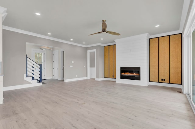 unfurnished living room featuring ceiling fan, light wood-type flooring, a fireplace, and ornamental molding