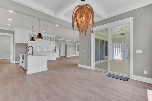 kitchen with a center island with sink, hanging light fixtures, ceiling fan, light wood-type flooring, and white cabinetry