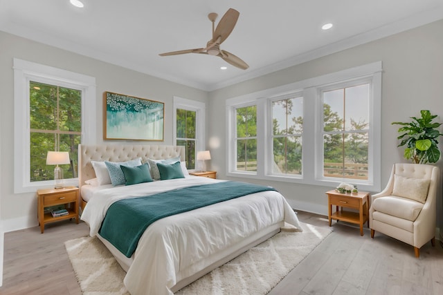 bedroom with multiple windows, light hardwood / wood-style flooring, ceiling fan, and ornamental molding