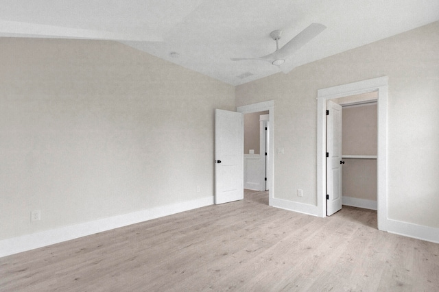 unfurnished bedroom featuring ceiling fan, a spacious closet, light hardwood / wood-style flooring, a closet, and lofted ceiling