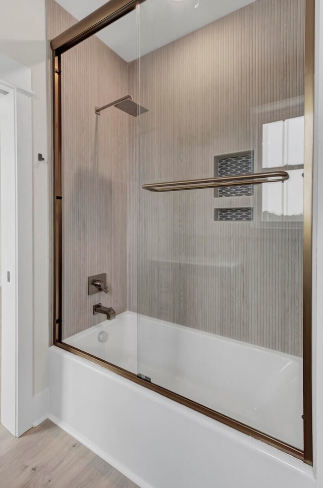 bathroom with enclosed tub / shower combo and wood-type flooring