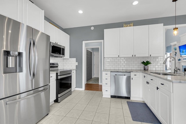 kitchen with tasteful backsplash, stainless steel appliances, light tile patterned flooring, white cabinetry, and a sink