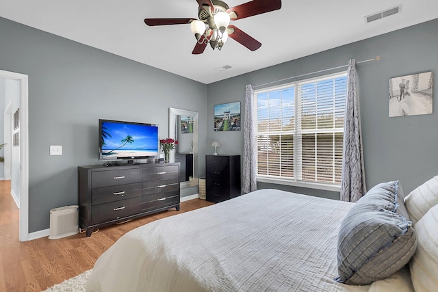 bedroom with visible vents, a ceiling fan, baseboards, and wood finished floors