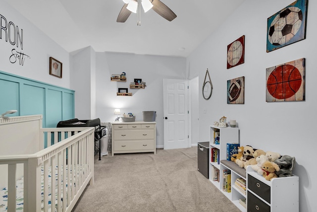 bedroom with ceiling fan, light carpet, and a crib