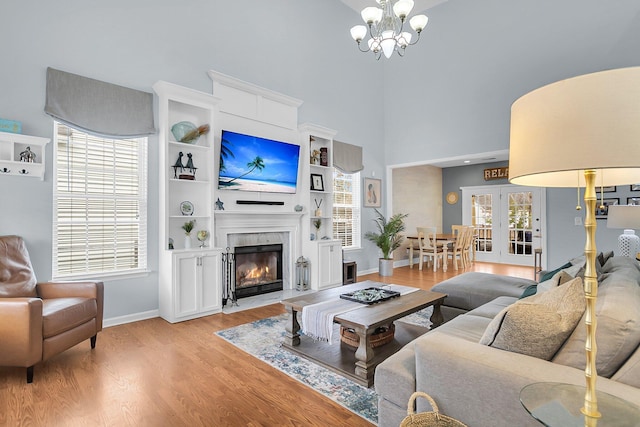 living room with a fireplace with flush hearth, plenty of natural light, light wood finished floors, and a chandelier