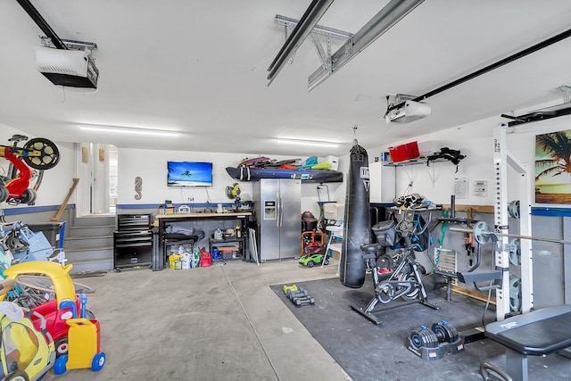 garage featuring stainless steel fridge, a workshop area, and a garage door opener