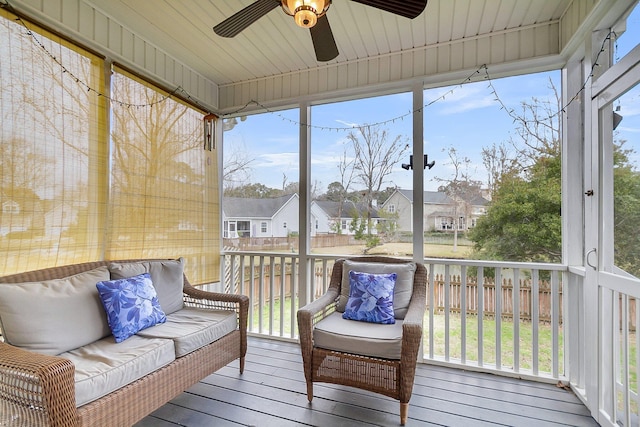 sunroom / solarium with a ceiling fan, a healthy amount of sunlight, and a residential view