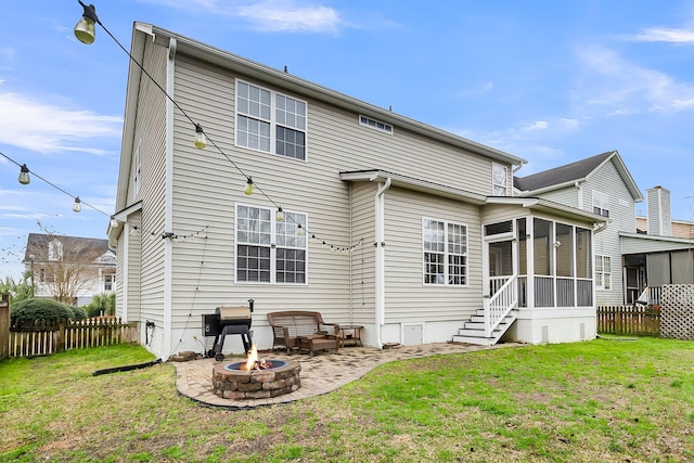 back of property with a lawn, fence, a sunroom, and an outdoor fire pit