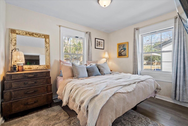 bedroom with multiple windows and dark hardwood / wood-style floors