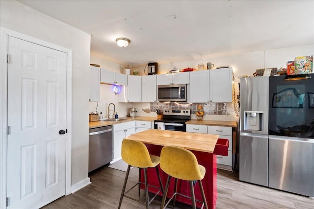 kitchen featuring a breakfast bar area, stainless steel appliances, light wood-type flooring, white cabinets, and sink