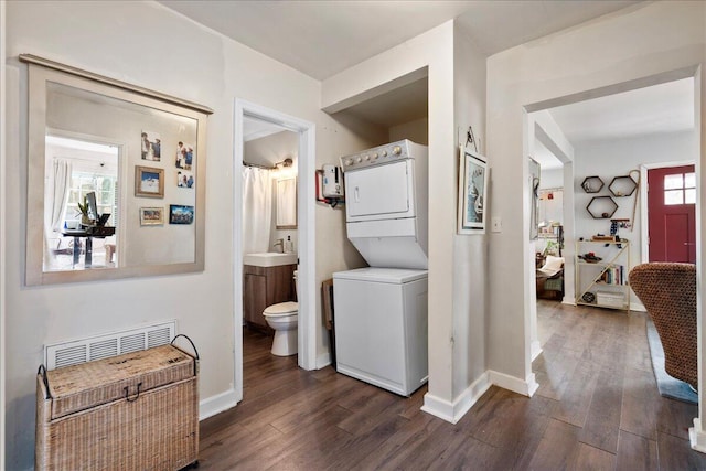 laundry room with dark hardwood / wood-style flooring, stacked washer / dryer, and sink