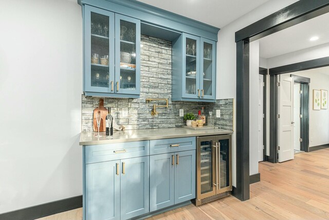 bar with blue cabinets, decorative backsplash, light hardwood / wood-style floors, and wine cooler