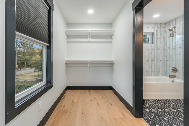 walk in closet with light hardwood / wood-style floors