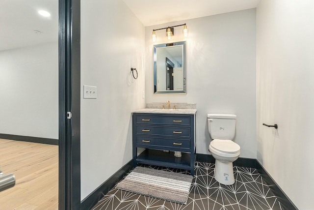 bathroom with toilet, wood-type flooring, and vanity