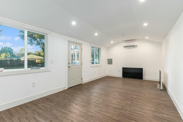 unfurnished living room with vaulted ceiling, a wall mounted air conditioner, and dark hardwood / wood-style floors