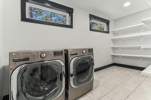 clothes washing area featuring light tile patterned floors, washer and clothes dryer, and plenty of natural light