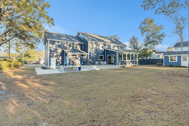 back of house featuring a patio area, a deck, a lawn, and a sunroom