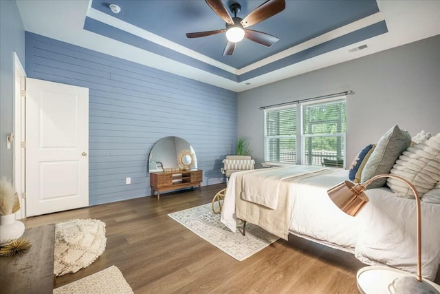 221 Lucca Dr, Summerville, SC 29486 - bedroom with wood walls, a tray ceiling, wood finished floors, visible vents, and a ceiling fan
