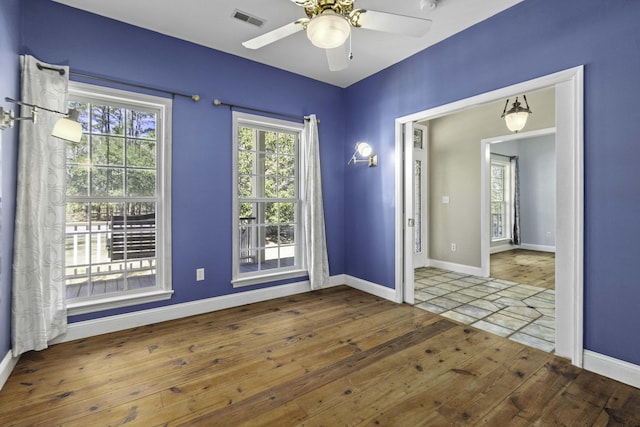 unfurnished room with visible vents, a ceiling fan, baseboards, and hardwood / wood-style floors